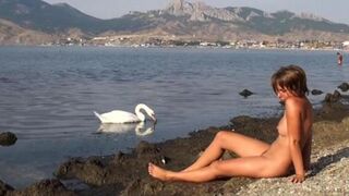 Nude beauty has fun on the river bank