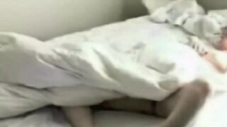 A man caresses himself with his hand in bed, unaware of the camera