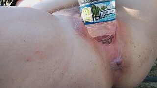 A woman reached a peak of pleasure while indulging in outdoor play with a water bottle