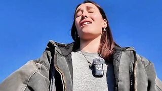 A petite brunette babe masturbates on the public beach, risking exposure