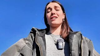 A petite brunette babe masturbates on the public beach, risking exposure